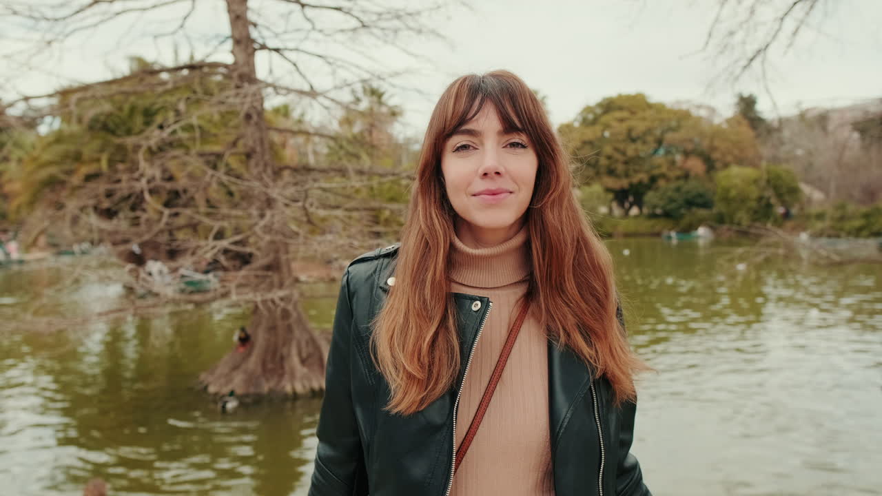 Giovane donna sorridente in un parco accanto a un lago