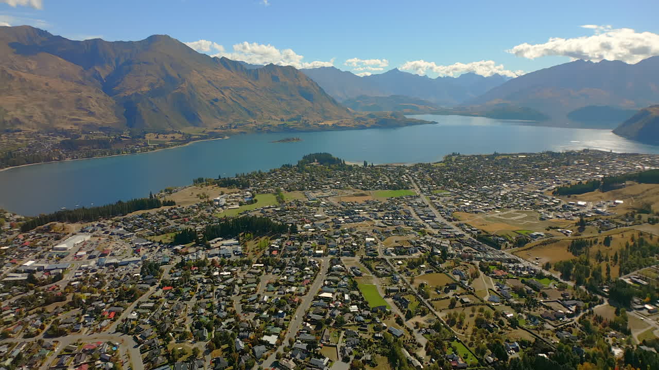 Wānaka village town community - aerial tilt up to reveal Lake Wanaka and the Remarkables Mountain Range