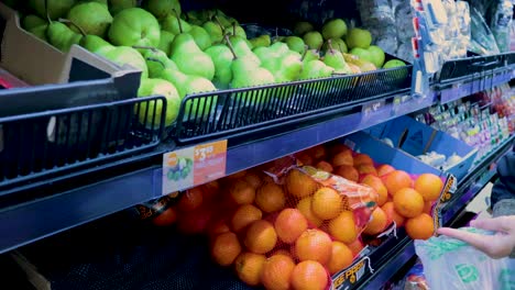 a person picks green pears from a supermarket shelf in melbourne, australia, under bright lighting, showcasing everyday shopping
