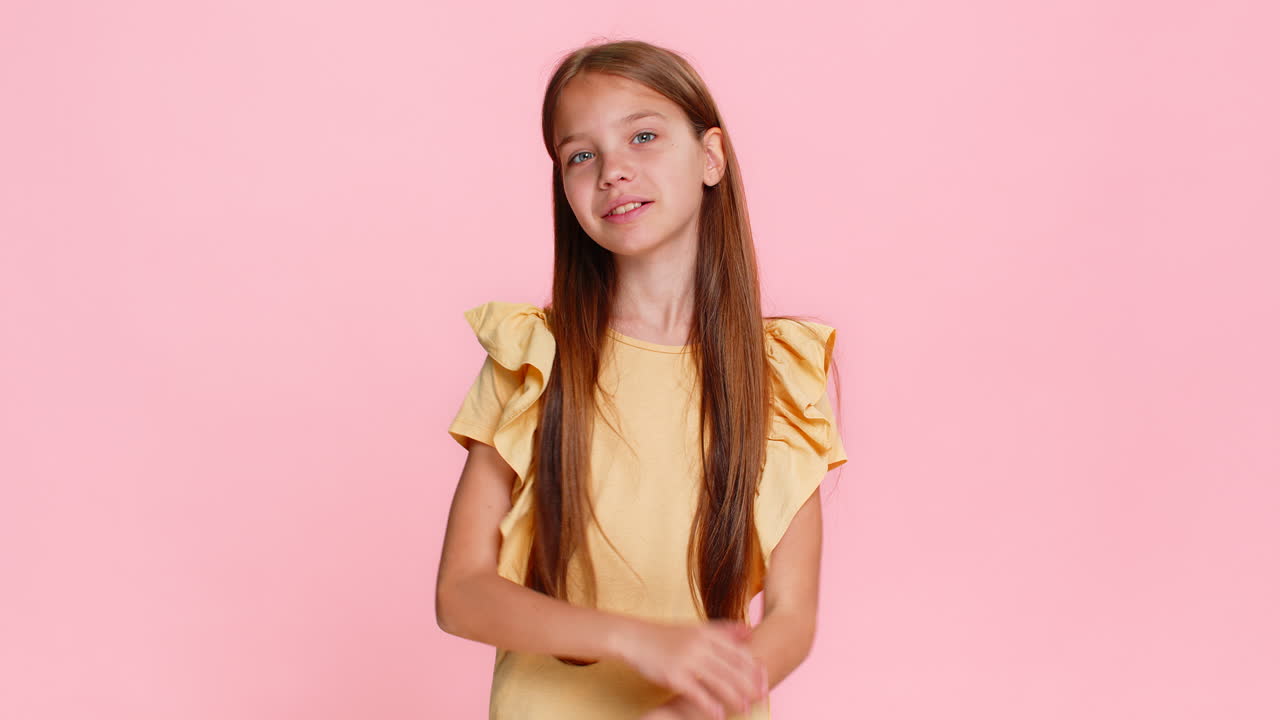 Child girl kid happily waving and smiling hello in playful mood greeting someone in front of camera
