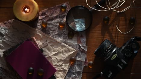 beautiful vintage background with ancient maps, a film camera, a book, a candle some stones and a magnifying glass