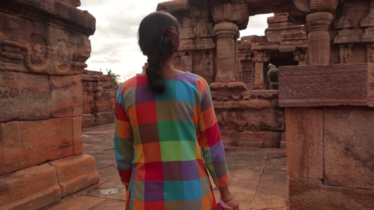 Plan moyen rapproché, vue de dos, suivant une touriste dans les ruines d'un ancien temple en Inde - Femme marchant seule sur un site archéologique en ruine
