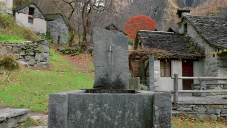 Durch-Einen-Wasserhahn-Fließt-Frisches-Wasser-Aus-Einem-örtlichen-Bach,-Mitten-Im-Dorf-Der-Steinhäuser-In-Cavergno,-Im-Bezirk-Vallemaggia,-Kanton-Tessin,-In-Der-Schweiz