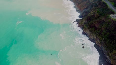 sand washed from beach making beautiful patterns in blue green ocean water in big sur california