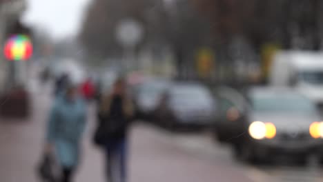 personas borrosas caminando rápidamente bajo la nieve que cae en la ciudad de invierno