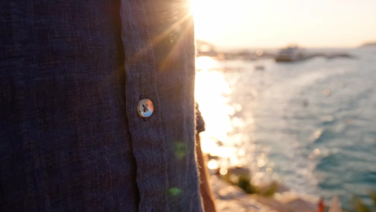 Un tramonto sereno sull'acqua, che mostra la spalla e la maglietta di una persona vicino alla riva, evidenziando momenti tranquilli con bagliori di luce solare che si riflettono sulle onde.