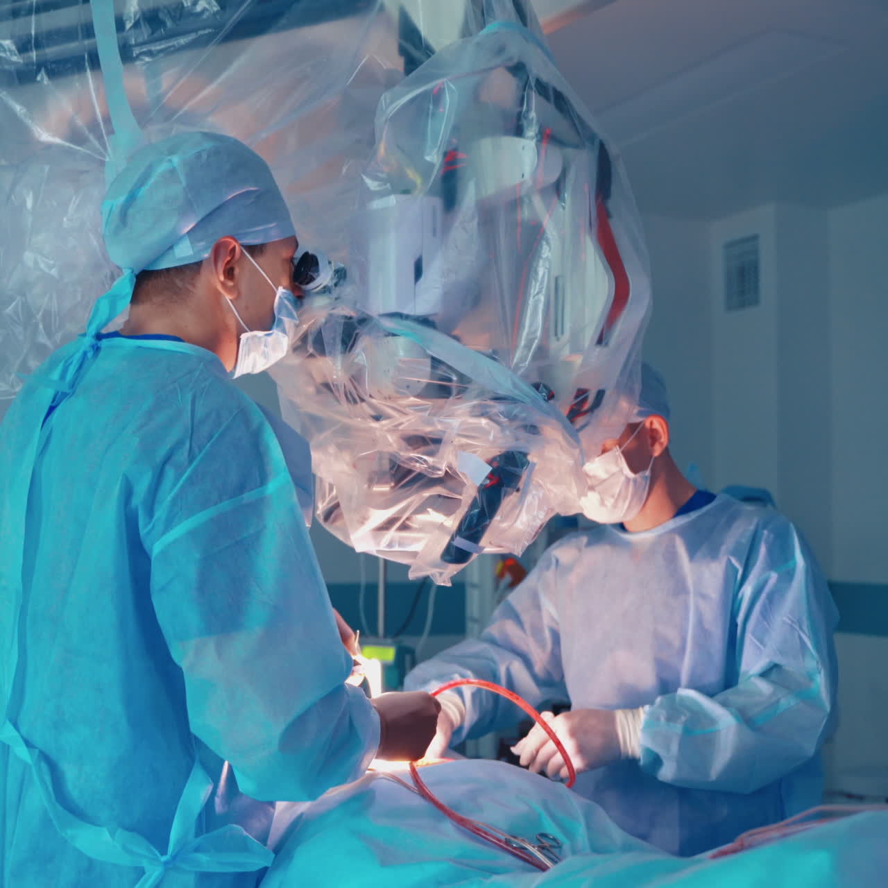 Work of surgeons in the modern operating room. Medical specialists perform a surgery through the microscope in clinic.