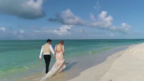 couple grown and bride walking on white sand beach cayo de agia island