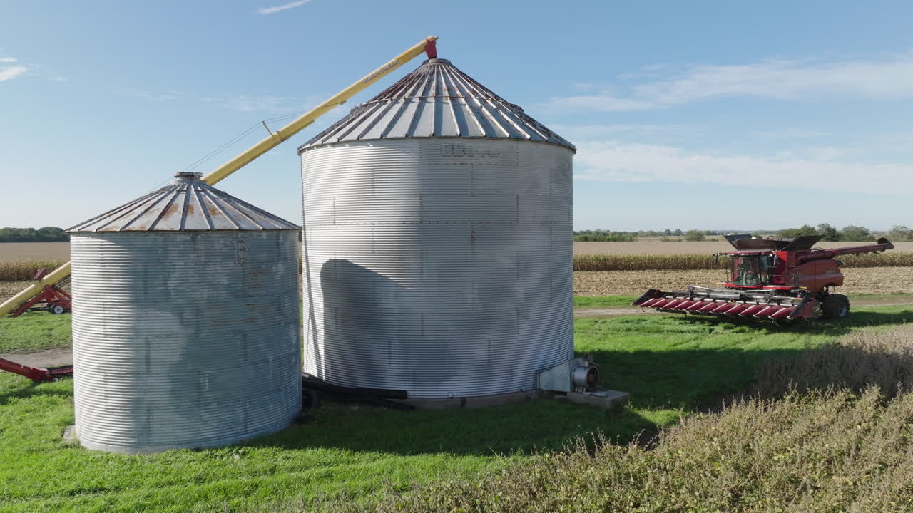 silos de contenedores de grano y cosechadora combinada en un campo agrícola rural, aérea