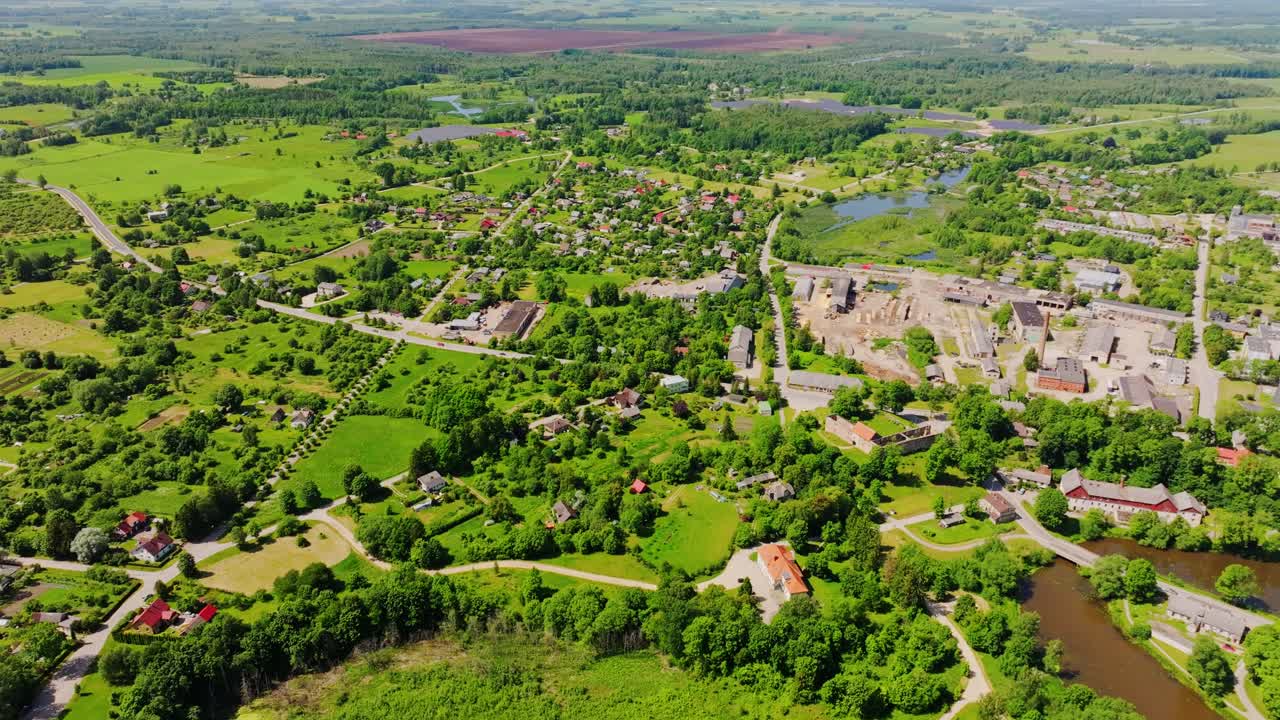 Drone glides sideways revealing Aizpute, lakes, green summer countryside, Latvia