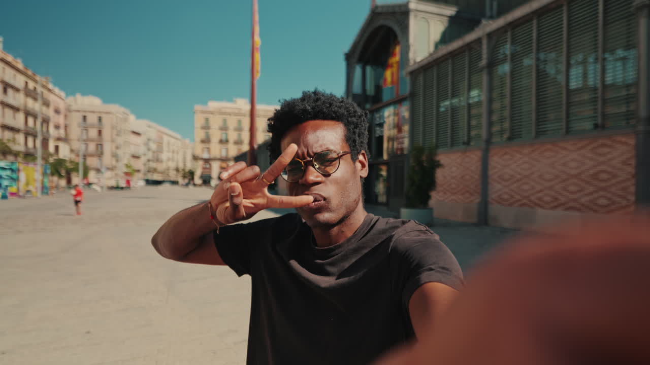 Giovane uomo afroamericano felice che registra un video selfie in una piazza cittadina