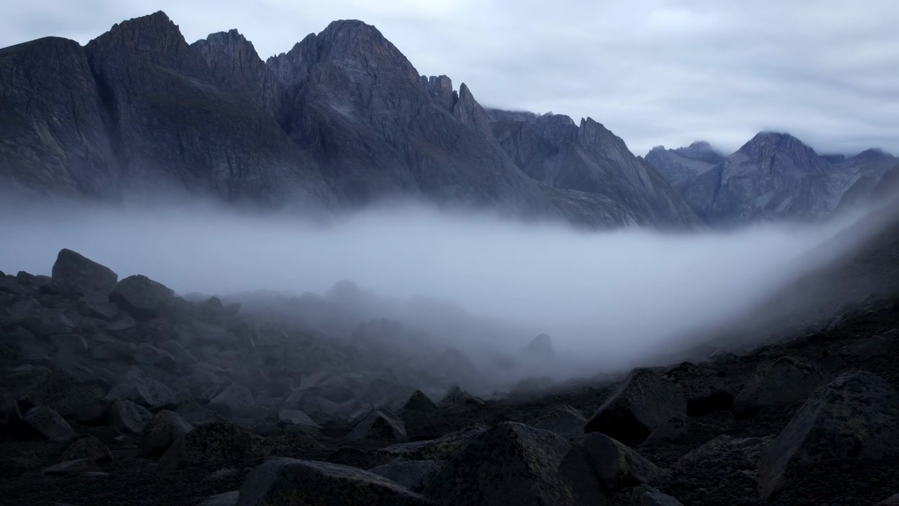 Fogfilled Rocky Valley At Dusk With Jagged Peaks And Low Cloud River Sliding Through Boulderstrewn Foreground,