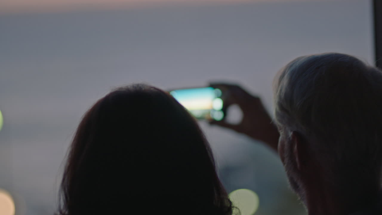 pareja de ancianos felices usando un teléfono inteligente fotografiando una hermosa puesta de sol en una habitación de hotel disfrutando de un exitoso estilo de vida de jubilación en vacaciones compartiendo vacaciones románticas