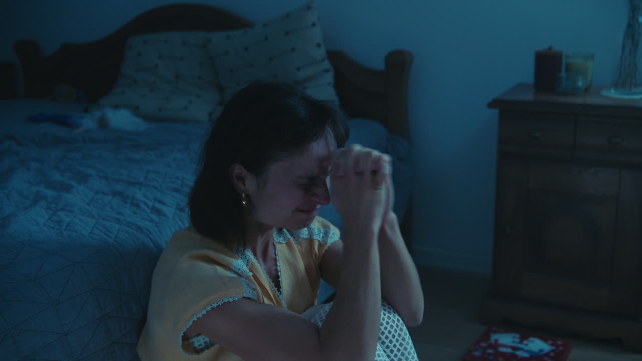 A traumatised and disoriented girl sits on the bedroom floor