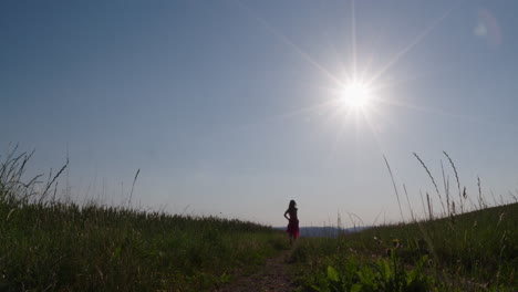 female silhouette runs towards the sun