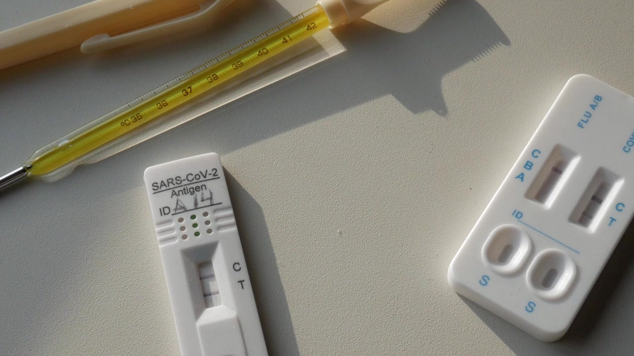 テーブルの上に置かれた複数のCOVID検査キットと体温計のパンニングビュー