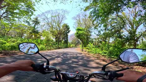 a man's pov riding a motorbike on a clear and sunny day, through a jungle road on ometepe island, nicaragua