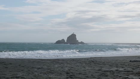 Rocks-and-lighthouse-view-from-Whatipu-Beach,-Omanawanui,-New-Zealand