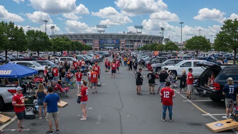a vibrant tailgating scene at a sports venue with enthusiastic fans gathered in red jerseys, enjoying food, games, and the pre-game atmosphere under a clear sky