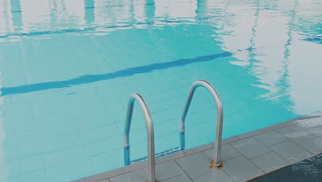 Tracking-Shot-Of-Empty-Professional-Swimming-Pool-With-Steps,-Blue-Water-And-Racing-Lane-Dividers