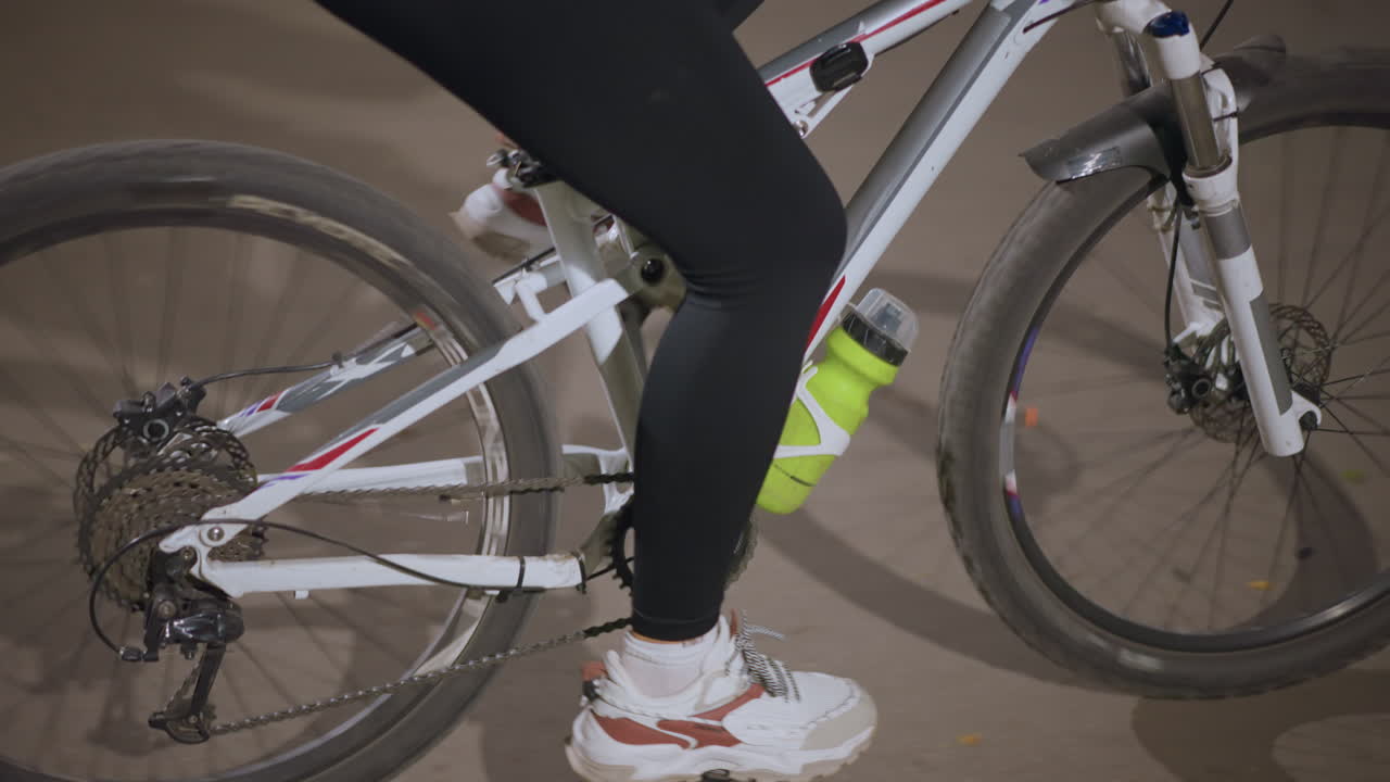 Night Cycling Scene, Rider Pedals Smoothly Along Nighttime Path, Close View Of Bike Wheel And Rider In Night Setting, Rider Pedal Steadily On Bike Through Nighttime Park With Trees Passing By