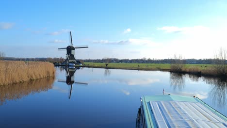 Whisper-boat-sailing-on-an-autumn-day-at-Kinderdijk-with-a-beautiful-reflection-in-the-water