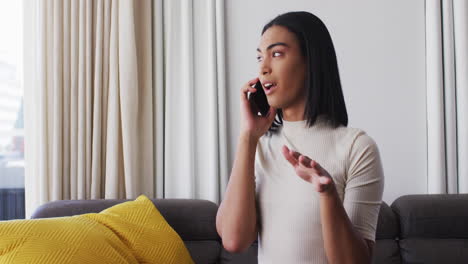 Gender-fluid-male-talking-on-smartphone-while-sitting-on-the-couch-at-home