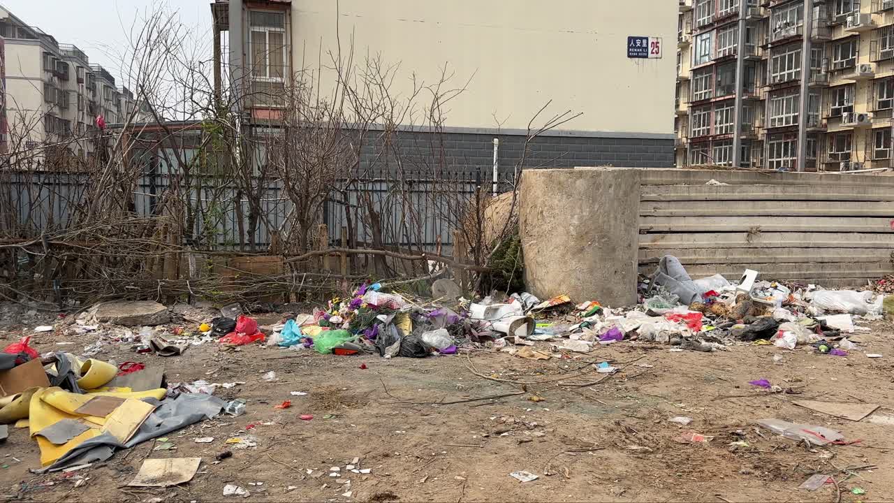 Unmanaged dangerous waste and terrible pollution next to a poor residential area in China. Unhealthy living environment surrounded by trash. Plastic pollution. Smoke coming from garbage on the street