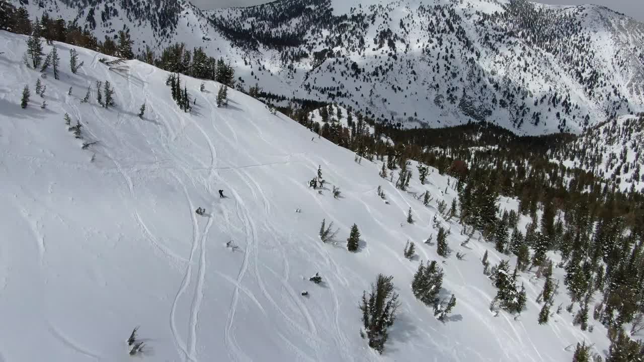4k 에픽 항공 영상 스키 선수가 겨울 동안 캘리포니아 타호 호수에서 산의 얼굴을 폭격하고 산꼭대기에 눈 폭풍이 오고 있습니다.
