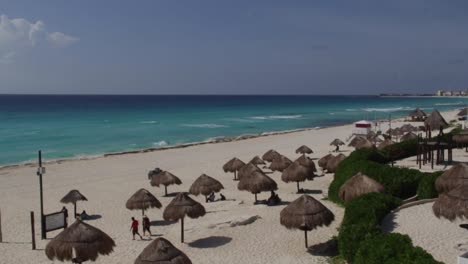 Amplia-Toma-Superior-En-La-Playa-De-Cancún,-Palapas-Y-Océano-Al-Frente.