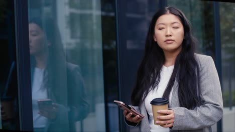 low angle view of business chinese woman walking in the city and texting phone