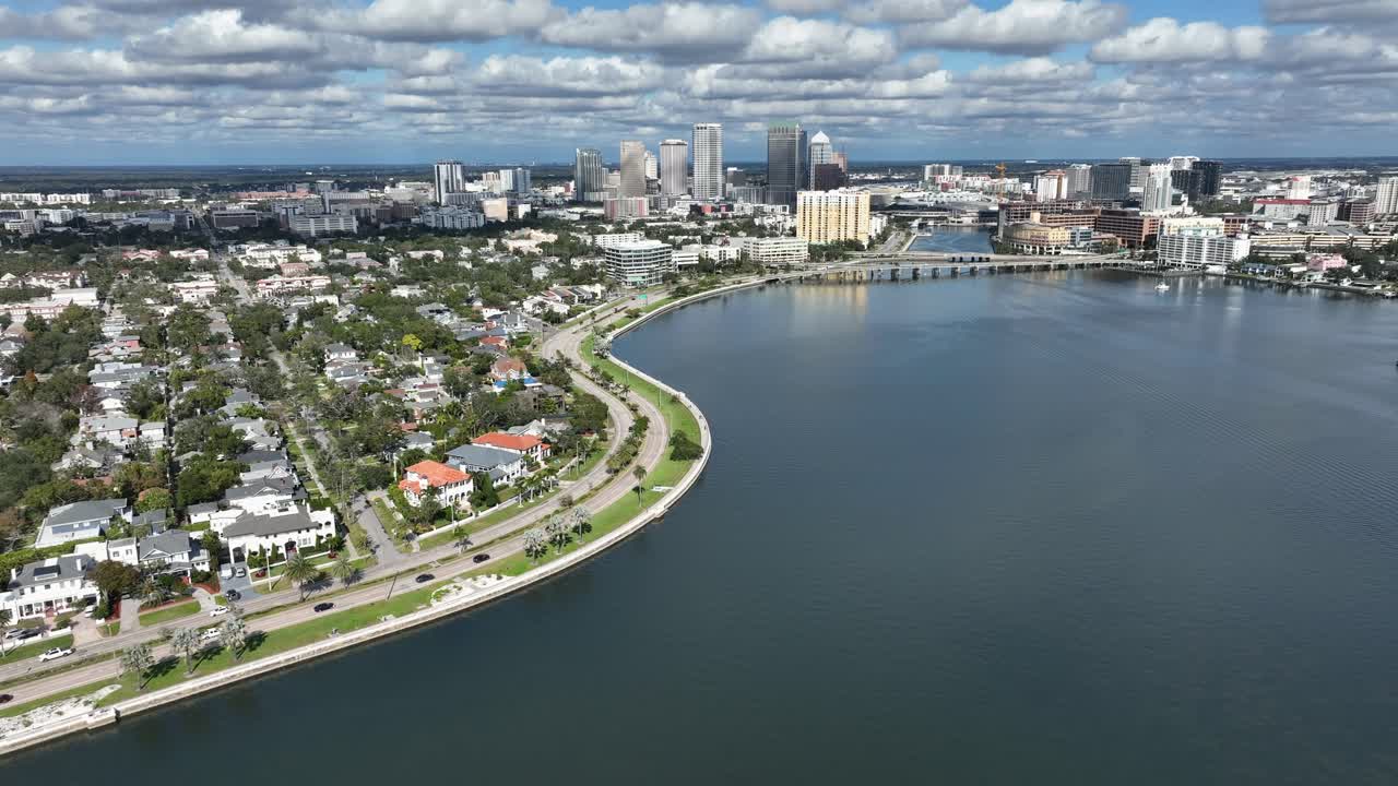 Vista de drone do Hyde Park em Tampa, Flórida, mostrando casas costeiras à beira-mar, estradas costeiras sinuosas, águas calmas da baía e horizonte do centro da cidade sob o céu claro durante o dia nos EUA. Plano geral
