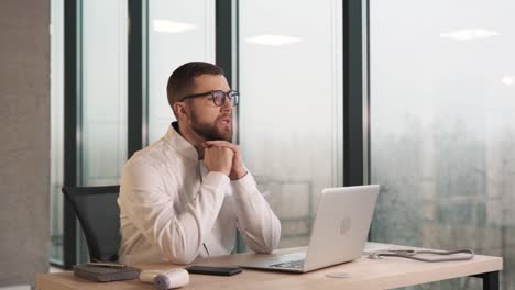 a young man sits in a modern clinic at a laptop and thinks about work