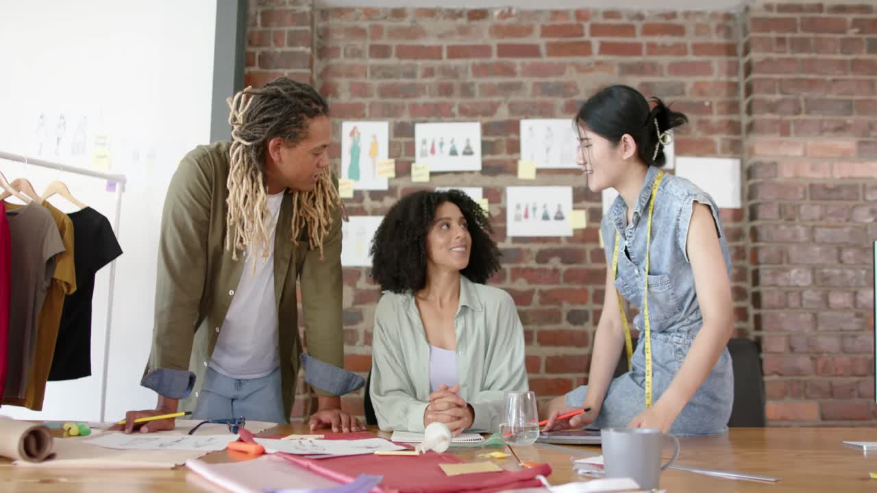 Happy diverse designers discussing project in fashion design studio in slow motion