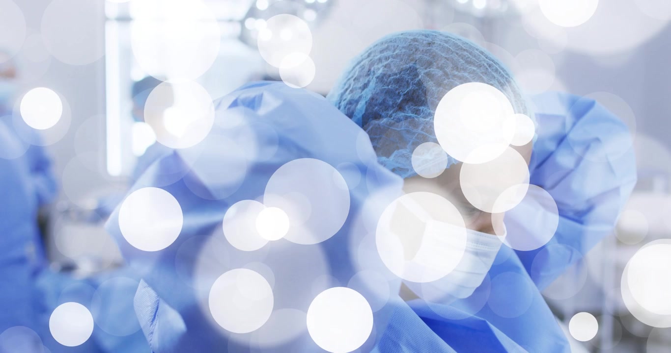 Chirurgyně připravující se na operaci, utahující si plášť a masku, s animovaným bokeh překrytím.