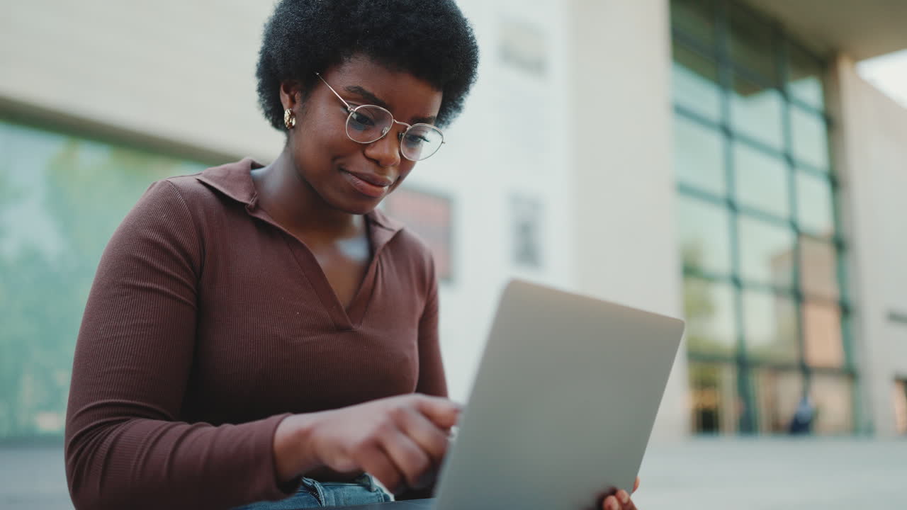Young female entrepreneur typing email working on laptop outdoors