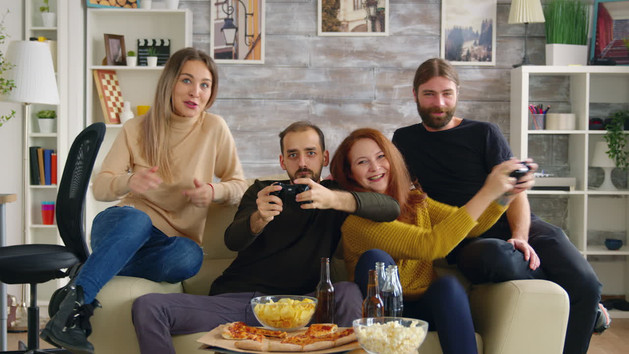 Innostunut mies pelaamassa videopelejä ja yrittää saada ystävänsä häviämään.