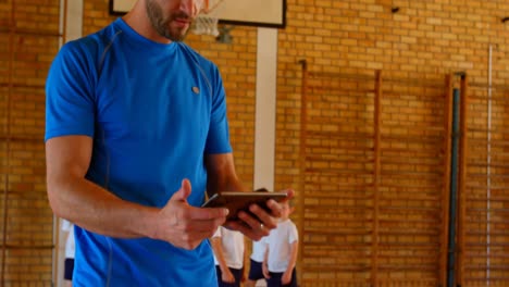 Entrenador-De-Baloncesto-Usando-Tableta-Digital-En-La-Cancha-De-Baloncesto-De-La-Escuela-4k
