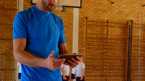 entrenador de baloncesto usando tableta digital en la cancha de baloncesto en la escuela 4k