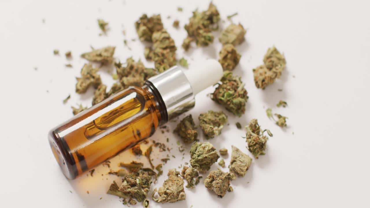 Video di infiorescenze di marijuana e flacone di estratto di CBD su sfondo bianco