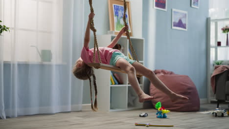 Blonde-preschooler-girl-with-long-braids-sits-on-swing