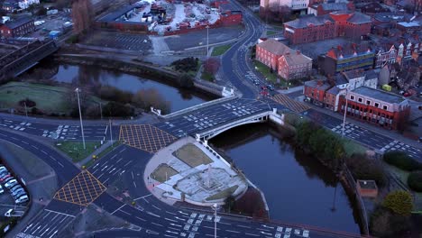 Aerial-early-morning-city-street-traffic-commuting-intersection-lanes-crossing-curved-river-birdseye-orbit-right