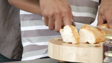 Close-up-of-father-and-son-cutting-bread-in-the-kitchen