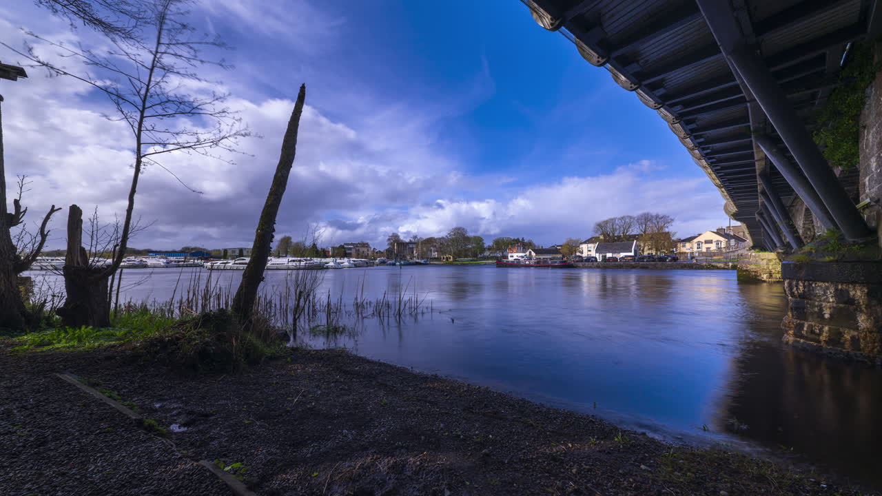 Timelapse of Carrick on Shannon town bridge in county Leitrim and Roscommon with river Shannon in the foreground and traffic, people and fast moving daytime clouds in Ireland