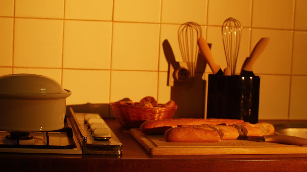 Golden sunlight casts a cozy glow on a rustic kitchen counter with fresh bread and baking tools