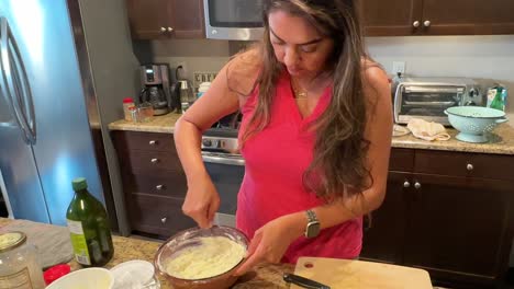 hispanic latina woman mixing batter for a homemade recipe in kitchen