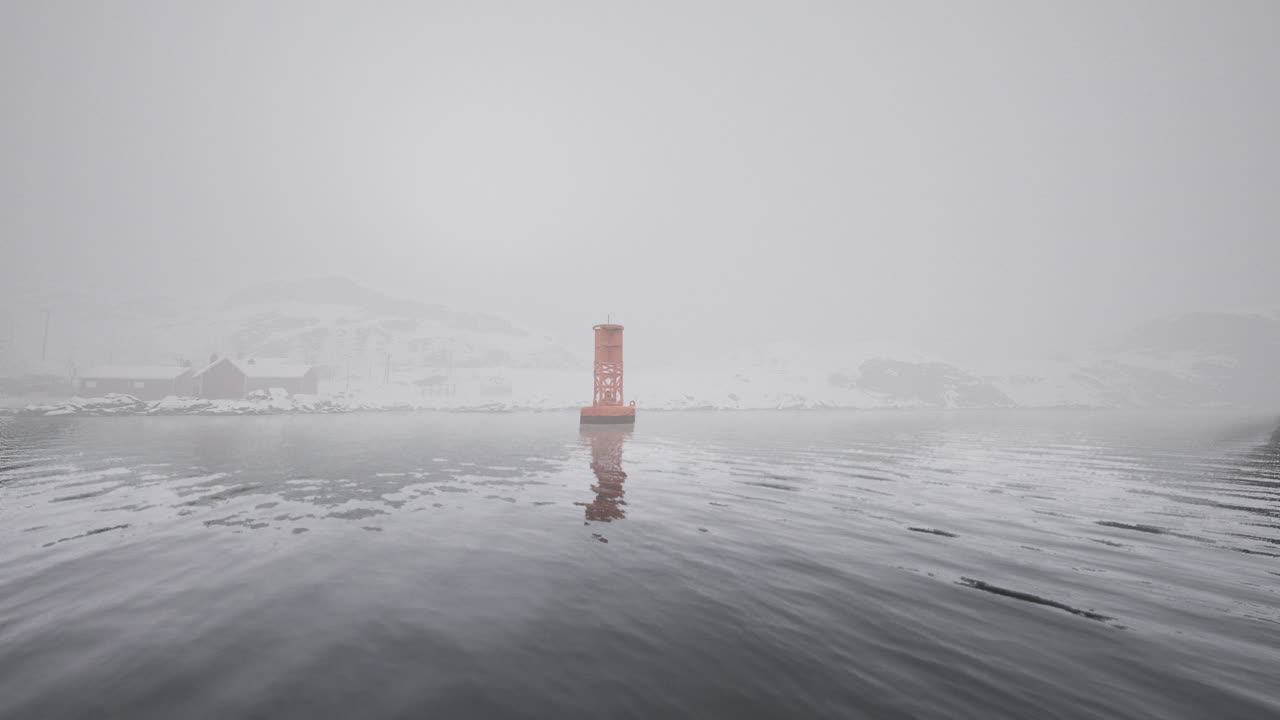 Fog envelops the lighthouse on a calm morning in a coastal harbor