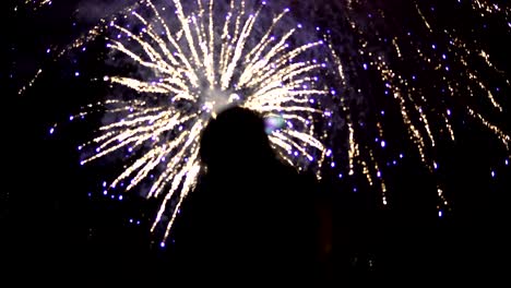 la niña toma fotos de fuegos artificiales en un teléfono móvil. silueta en el fondo del cielo iluminado por luces