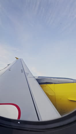 view from a plane window of the sky with the wing of the plane in shot in vertical