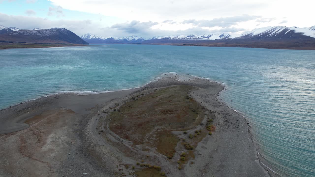 Peninsula With Turqouise Waters Of Lake Tekapo In South Island, New Zealand. Snow-capped Mountains In Background. aerial shot